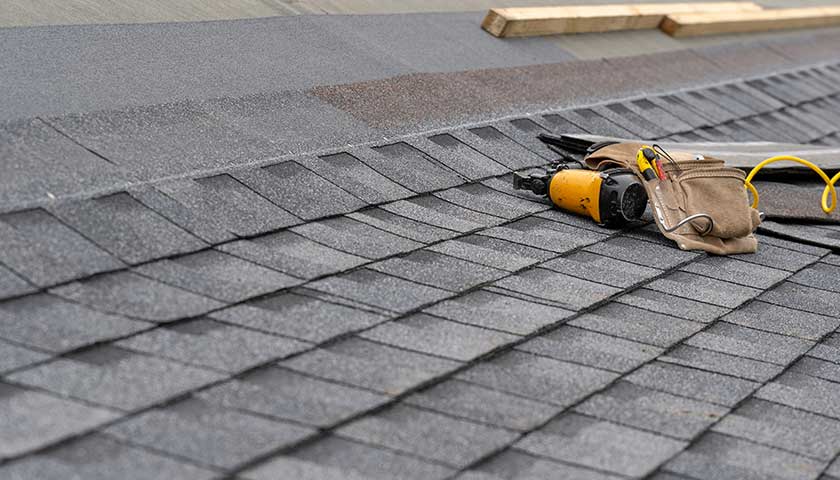 Asphalt tile roof and tool belt lying on new house