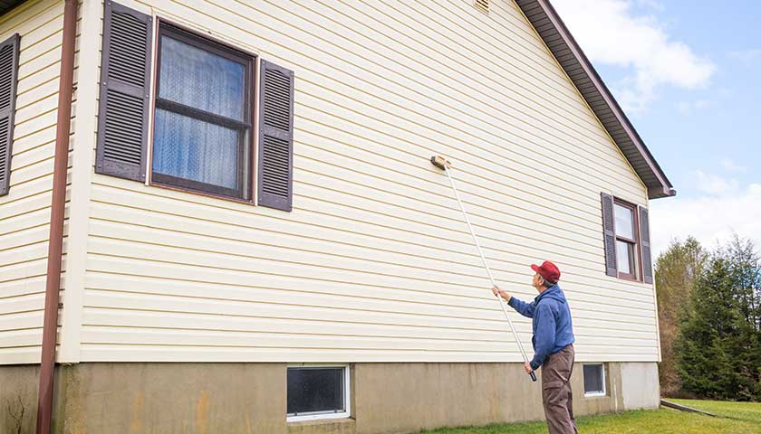 Homeowner washing house vinyl siding