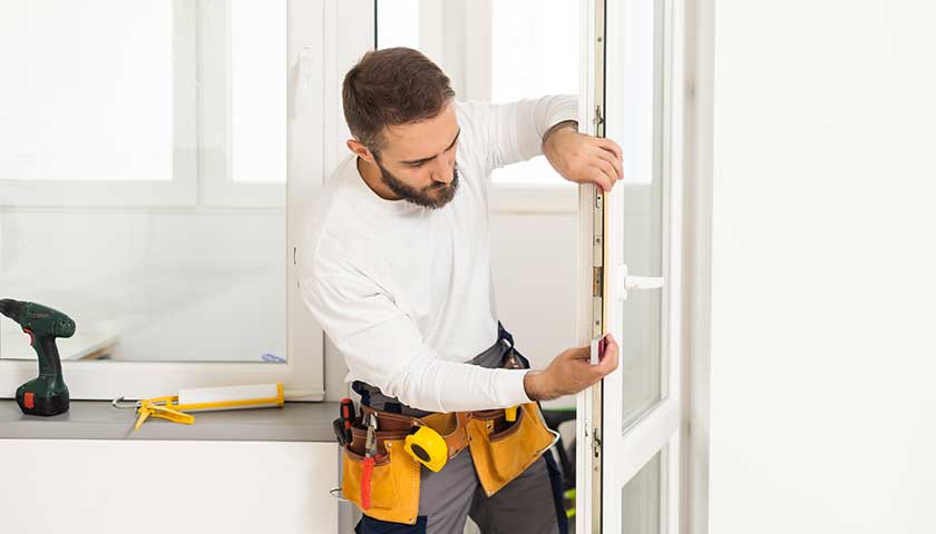 Service man installing window with screwdriver
