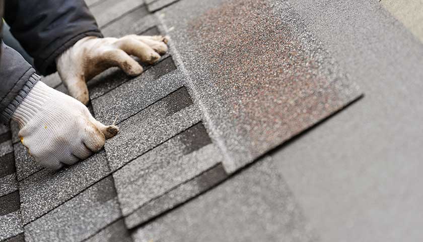 Workman install tile on roof of new house